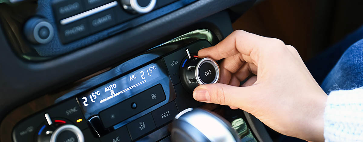 Woman adjusting air conditioner in car